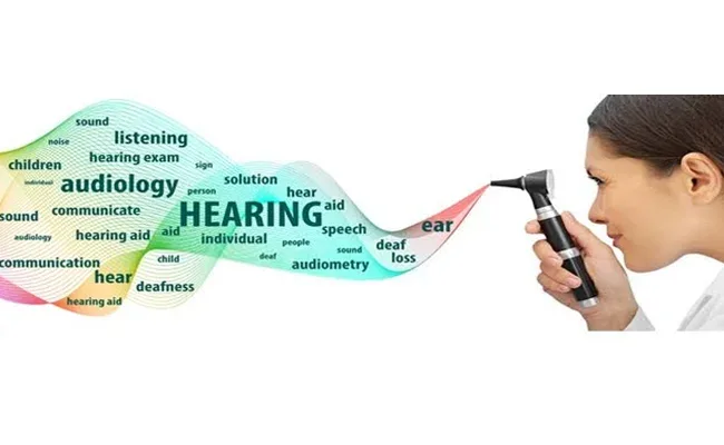 Audiologist looking through an otoscope at a wave of hearing-care words