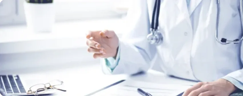 Doctor in a white coat at a desk with a laptop