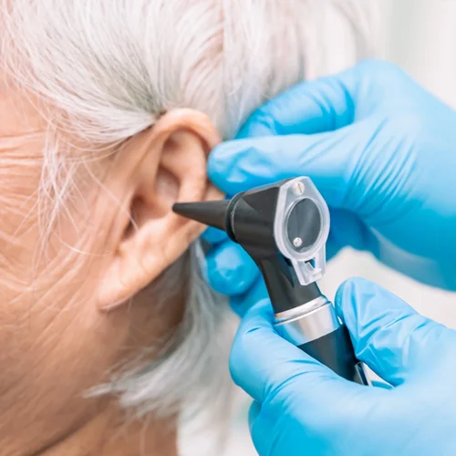 Gloved audiologist examining an ear with an otoscope
