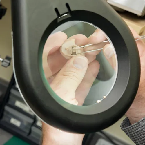 Hearing aid inspected under a magnifying lamp