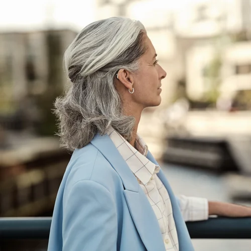 Woman with silver hair wearing a discreet hearing aid